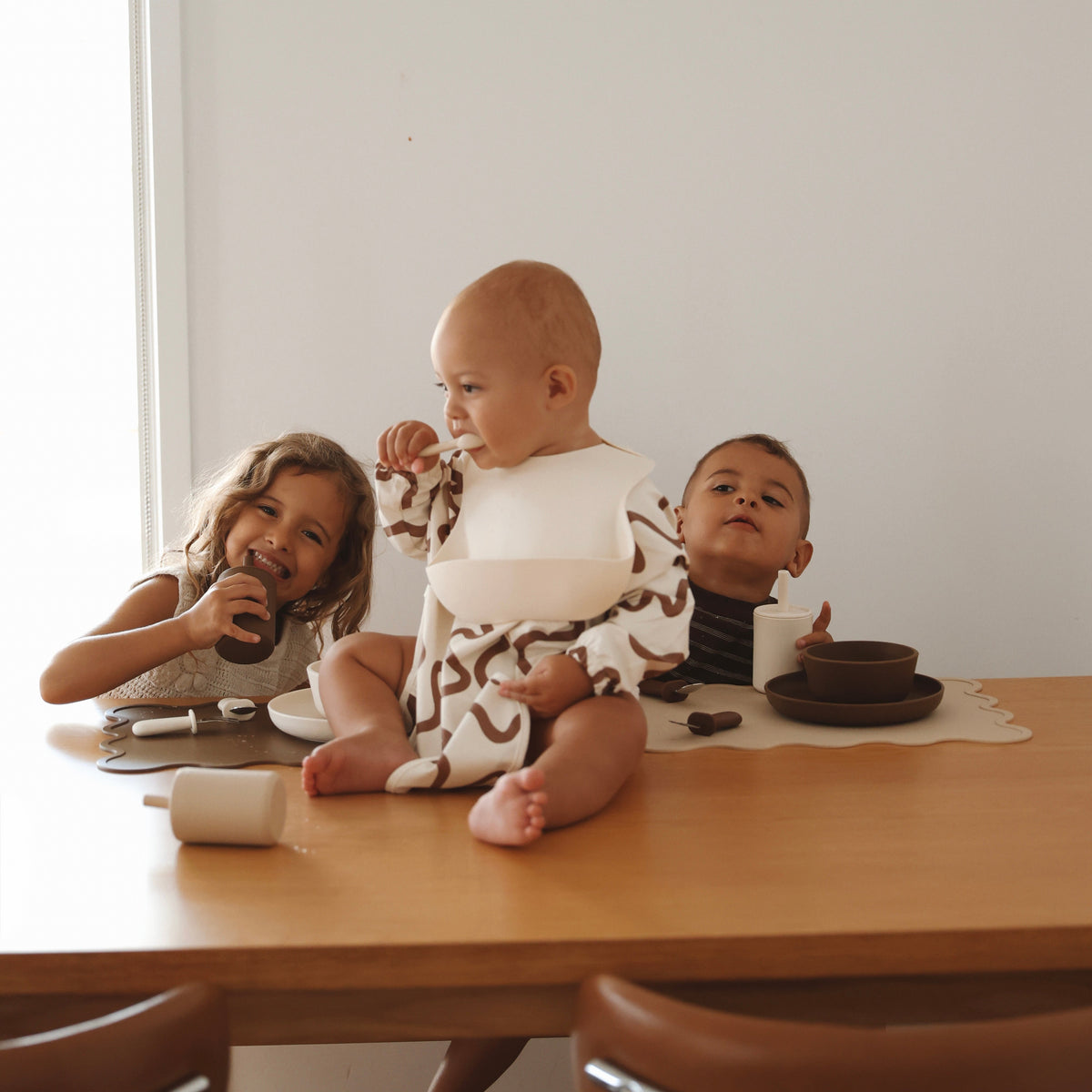 Three children sitting at a wooden table with Rommer dinnerware in creme, oat and mocha